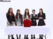 a group of young women are standing around a table .