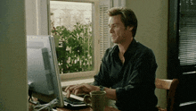 a man sits at a desk using a computer