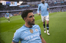a soccer player wearing an etihad airways jersey celebrates on the field