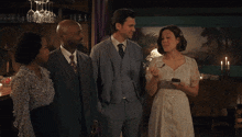a man in a suit stands next to two women