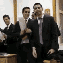 a group of men in suits and ties stand in a room
