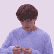a man in a blue sweater is holding a ring in his hand .