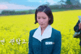 a woman in a blue jacket is standing in a field of yellow flowers ..