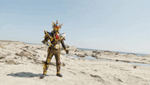a man in a black and gold armor stands in the desert holding a blue object