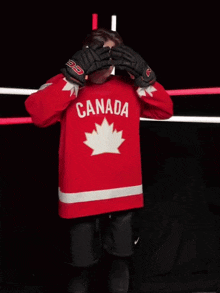 a hockey player wearing a red canada jersey stands in front of a camera