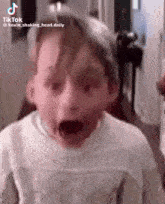 a young boy is making a funny face with his mouth open in a tik tok video .