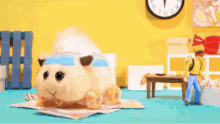 a stuffed animal is sitting on top of a magazine next to a table and a clock .