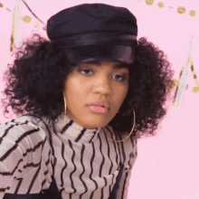 a girl with curly hair wearing a black hat and hoop earrings