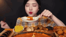 a woman in a plaid shirt is eating food with chopsticks and a spoon