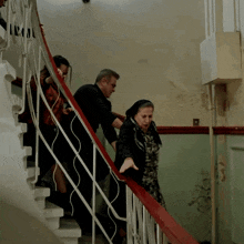 a group of people are walking down a set of stairs with a woman reaching for the railing