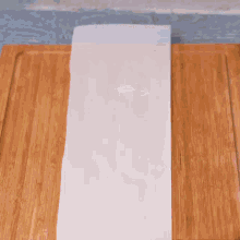 a bowl of liquid is being poured on a piece of paper on a cutting board .