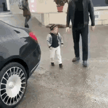 a little boy is walking next to a man in a black jacket .