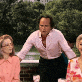 a man in a pink shirt is standing in front of two women