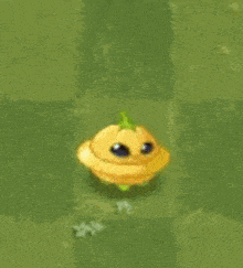 a yellow cartoon pumpkin with a green stem is sitting on top of a green field .