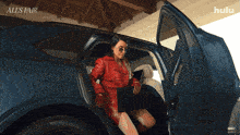 a woman in a red leather coat is getting out of a car with the hulu logo behind her
