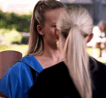 two women are standing next to each other and one of them is wearing a blue jacket .