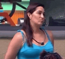 a woman in a blue tank top is standing next to a dog .