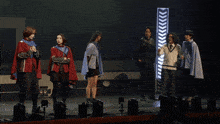 a group of people standing on a stage in front of a sign that says ' arrows ' on it