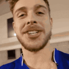 a close up of a man 's face with a beard wearing a blue shirt