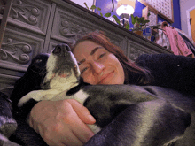 a woman is holding a black and white dog in her lap
