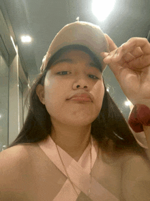 a girl wearing a baseball cap and a pink top takes a selfie