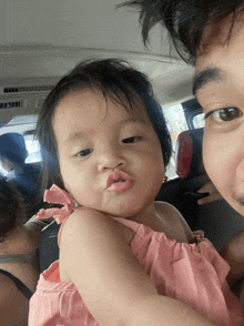 a man is holding a baby in his arms and the baby is making a face