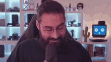 a man with glasses and a beard is sitting in front of a microphone