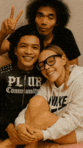 a woman wearing a nike sweatshirt sits next to a man wearing a jacket that says plur community