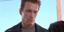 a man in a leather jacket is looking at a woman in a gray shirt .