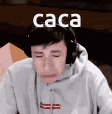 a young man wearing headphones is crying and the word caca is above him .
