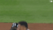 a group of baseball players are hugging on the field .
