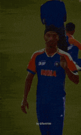 a man wearing a blue and orange india jersey stands on a field
