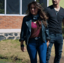 a woman in a leather jacket is walking next to a man