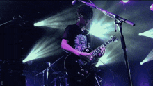a man playing a guitar in front of a microphone with the letter d visible