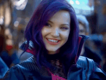 a woman with purple hair is smiling and wearing a black jacket .