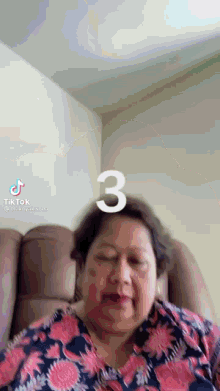 a woman is sitting in a chair with her eyes closed and a number three on her head .