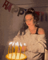 a woman blowing out candles on a birthday cake