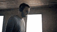 a man wearing headphones and glasses is standing in front of a window