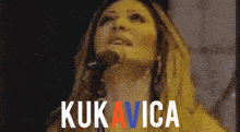 a woman singing into a microphone with the name kukavica written on the bottom