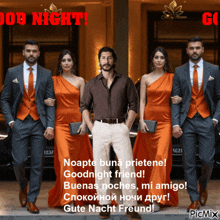 a man in a suit stands between two women in orange dresses and says goodnight friend
