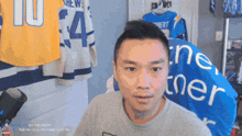 a man is sitting in front of a wall with jerseys hanging on it including one that says 10