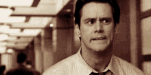 a man in a tie is making a funny face in a hallway .