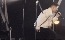 a man is singing into a microphone while standing on a stage .