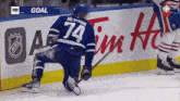 a hockey player with the number 74 on his back is kneeling on the ice