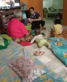 a woman in a pink shirt sits on the floor playing with children