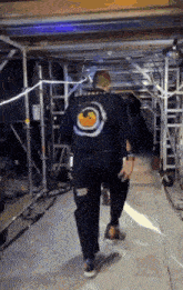 a man is walking down a hallway wearing a black shirt with a target on it