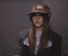 a woman wearing headphones and a hat that says no cool us on it