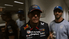 a man wearing a red bull shirt is talking to another man