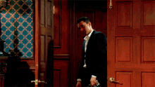 a man in a suit stands in front of a door