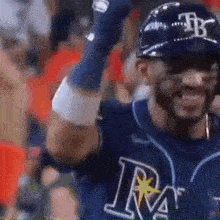 a baseball player is wearing a helmet and smiling while holding his arms in the air .